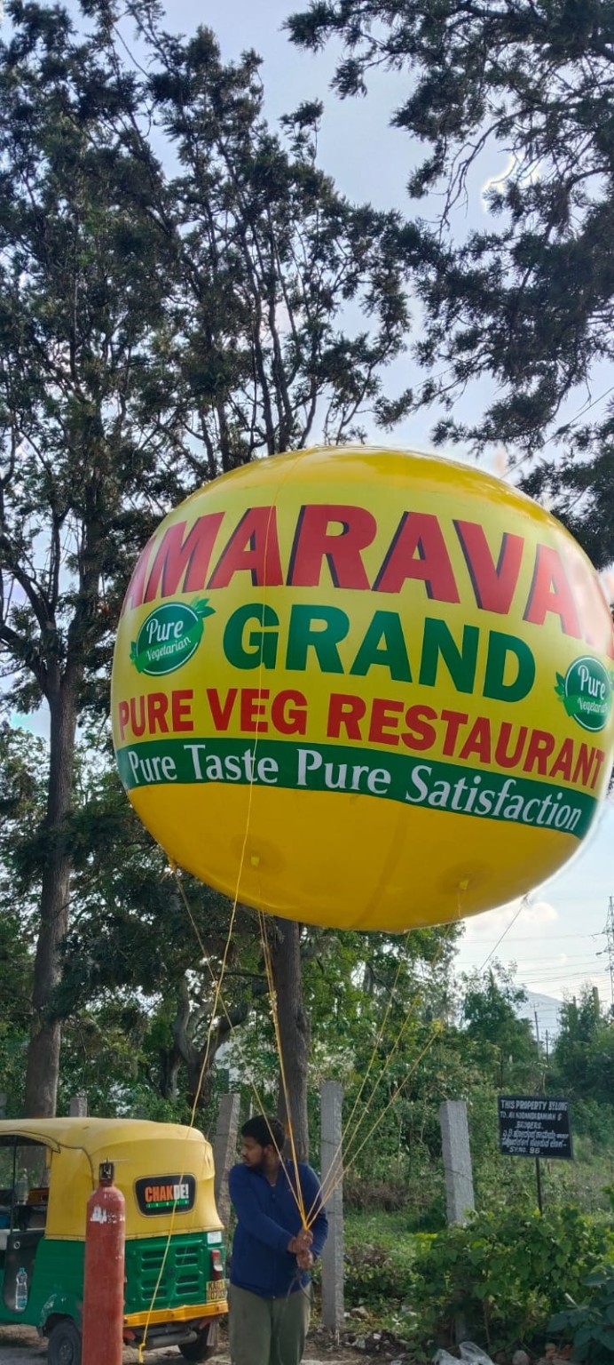 Yellow helium advertising balloon branded for a restaurant, tethered beside a roadside in Bangalore