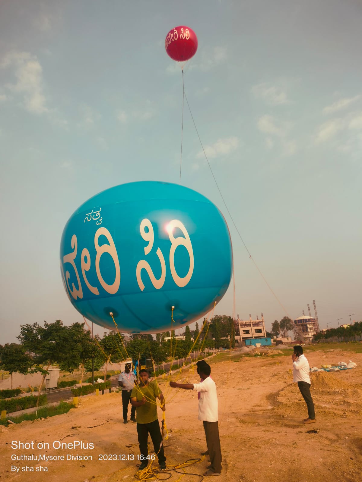 Twin tethered advertising sky balloons with Kannada branding at a Mysore layout launch